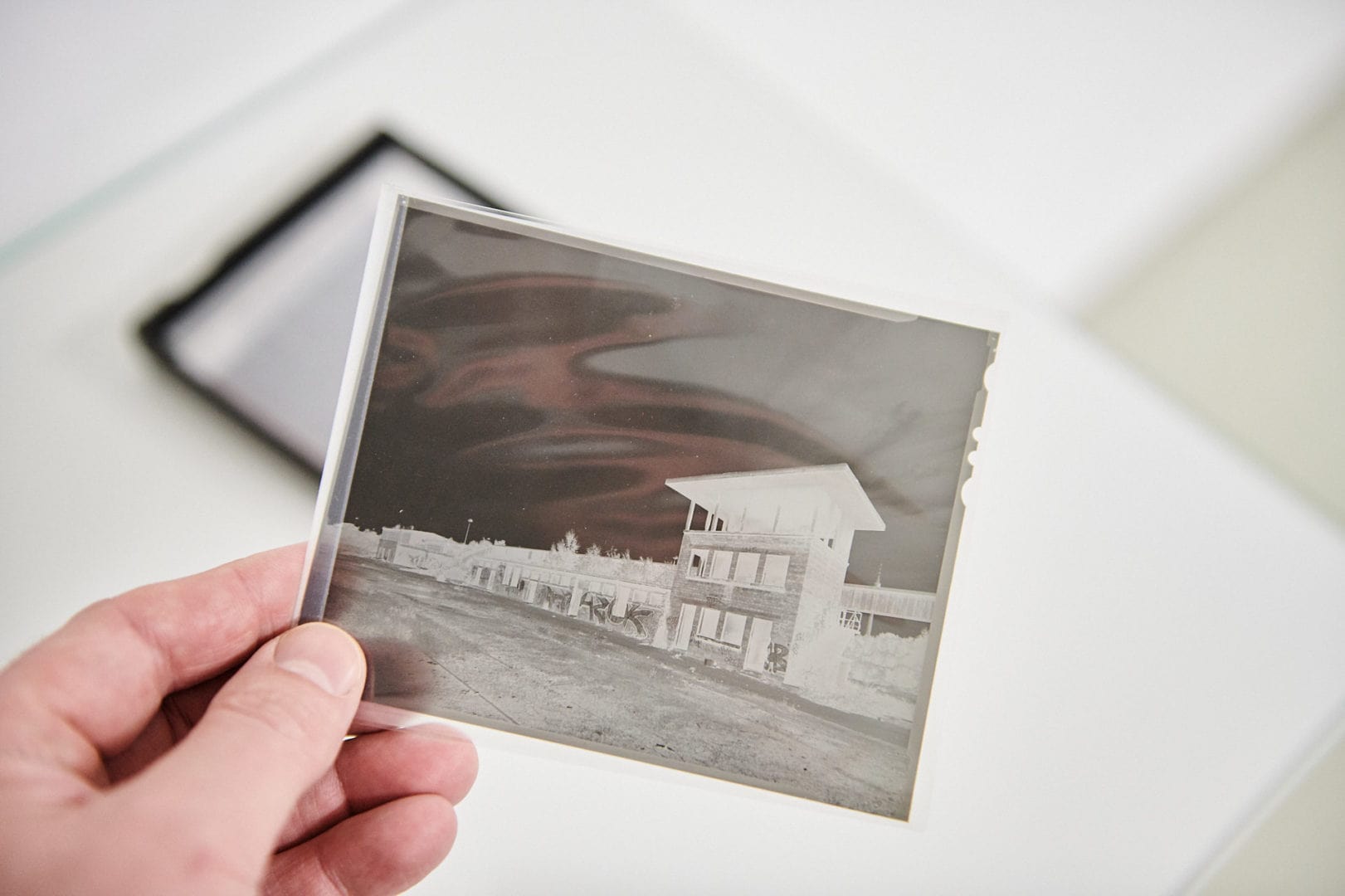 Fotograf hält Negativ eines Planfilms 4x5 in der Hand