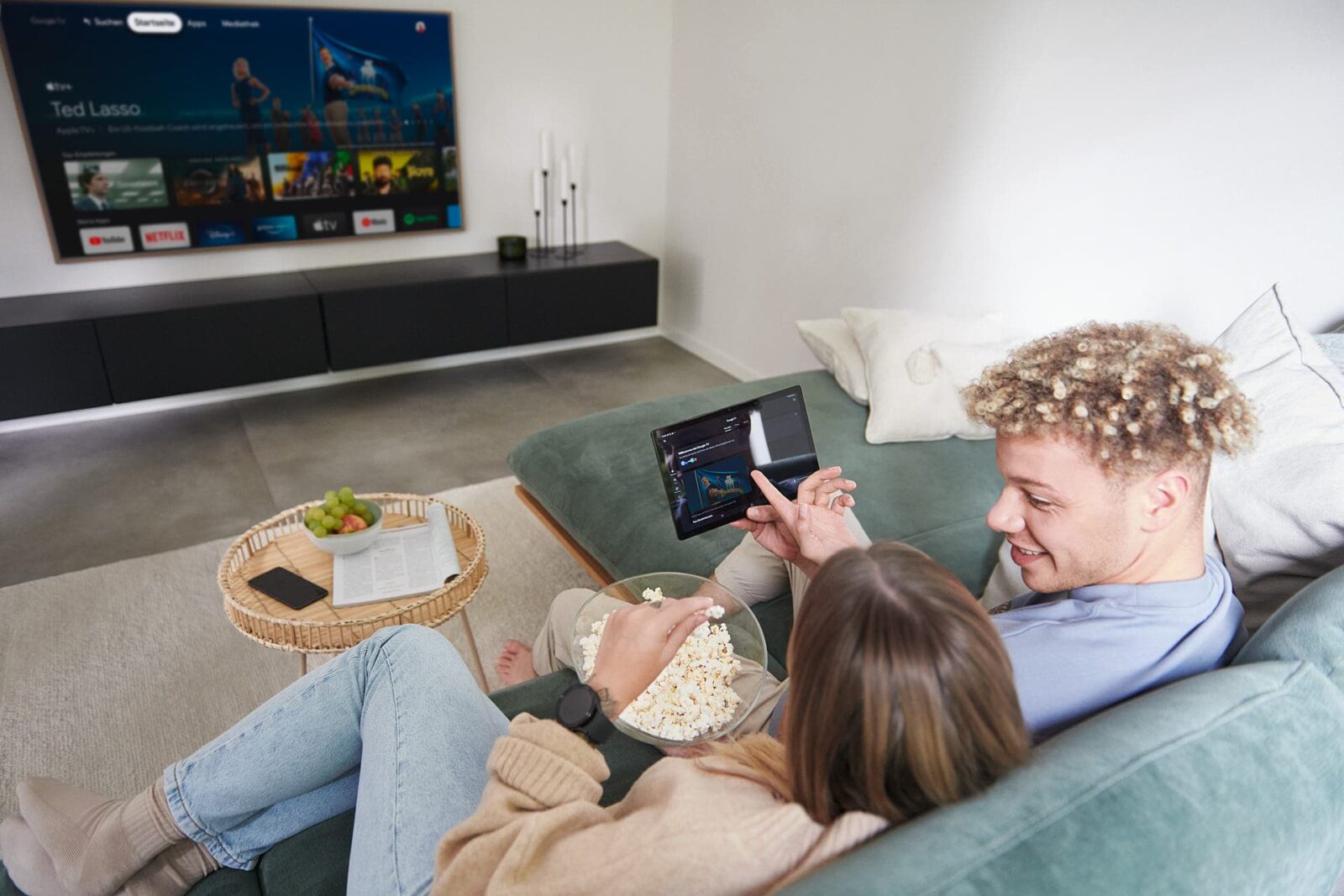 Werbefotografie eines Paares, das für eine Android-Kampagne auf einer Couch posiert und auf einem Tablet Filme streamt
