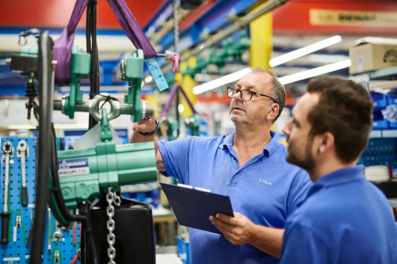 Zwei Menschen prüfen ein Produkt in einer Industrieproduktion. Das Mitarbeiterportrait zeigt die beiden Menschen am Arbeitsplatz