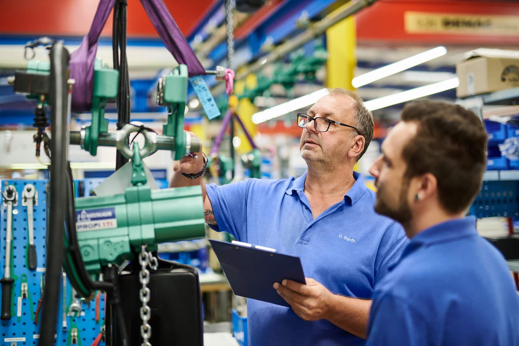 Zwei Menschen prüfen ein Produkt in einer Industrieproduktion. Das Mitarbeiterportrait zeigt die beiden Menschen am Arbeitsplatz