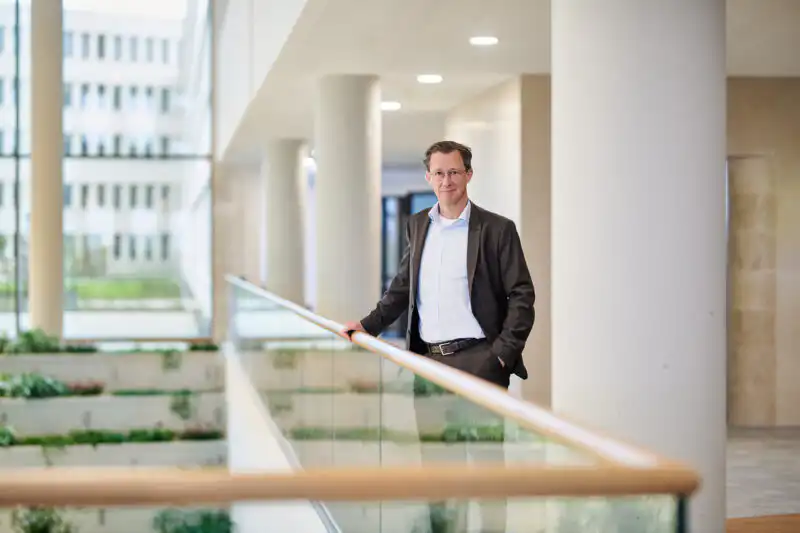 Corporate Portrait für das Unternehmen Materna. Der neue Mitarbeiter lehnt entspannt an einem Geländer in dem neuen Hauptquartier in Dortmund