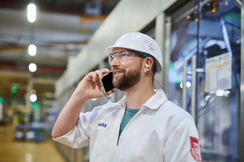 Ingenieur in weißem Helm telefoniert in einer Industriefertigung. Professionelle Unternehmensfotografie aus Dortmund.