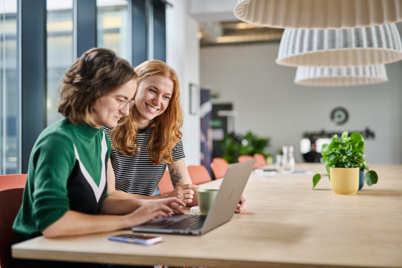 Zwei Frauen arbeiten gemeinsam an einem Laptop in einem modernen Büro - professionelle Unternehmensfotografie in Dortmund.