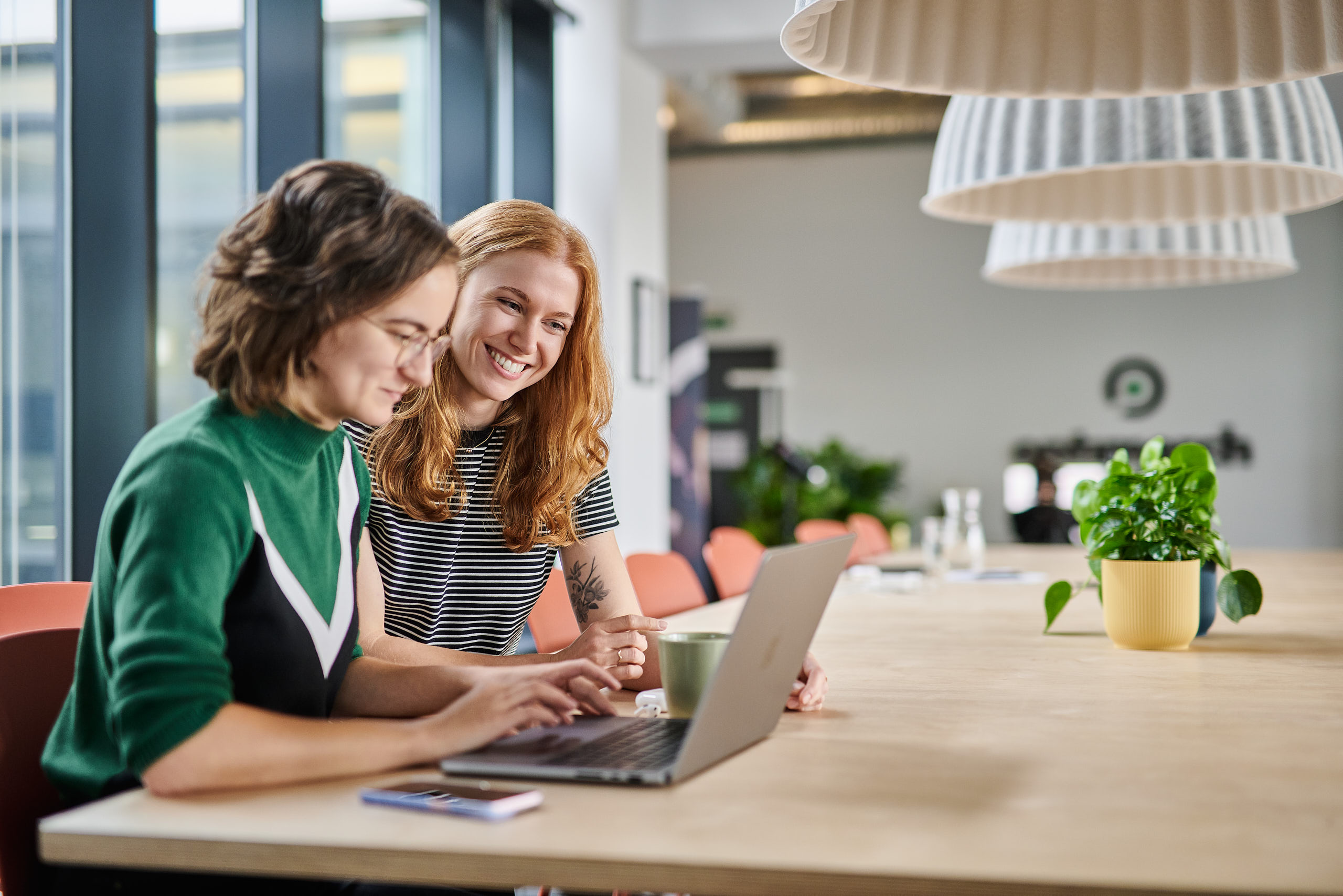 Zwei Frauen arbeiten gemeinsam an einem Laptop in einem modernen Büro - professionelle Unternehmensfotografie in Dortmund.