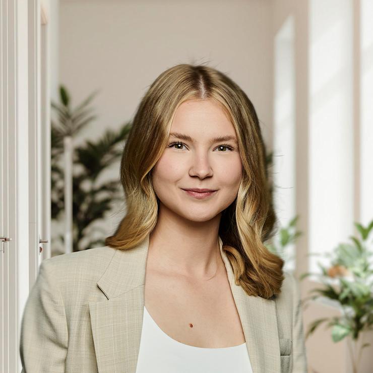 Corporate Portrait einer jungen Frau im beigen Blazer vor hellem Büro-Hintergrund mit Pflanzen, aufgenommen in Dortmund.