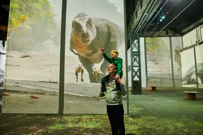 Vater mit Kind auf den Schultern in der immersiven Ausstellung Phoenix des Lumières Dortmund – Dinosaurier-Projektion – Fotograf Markus Mielek