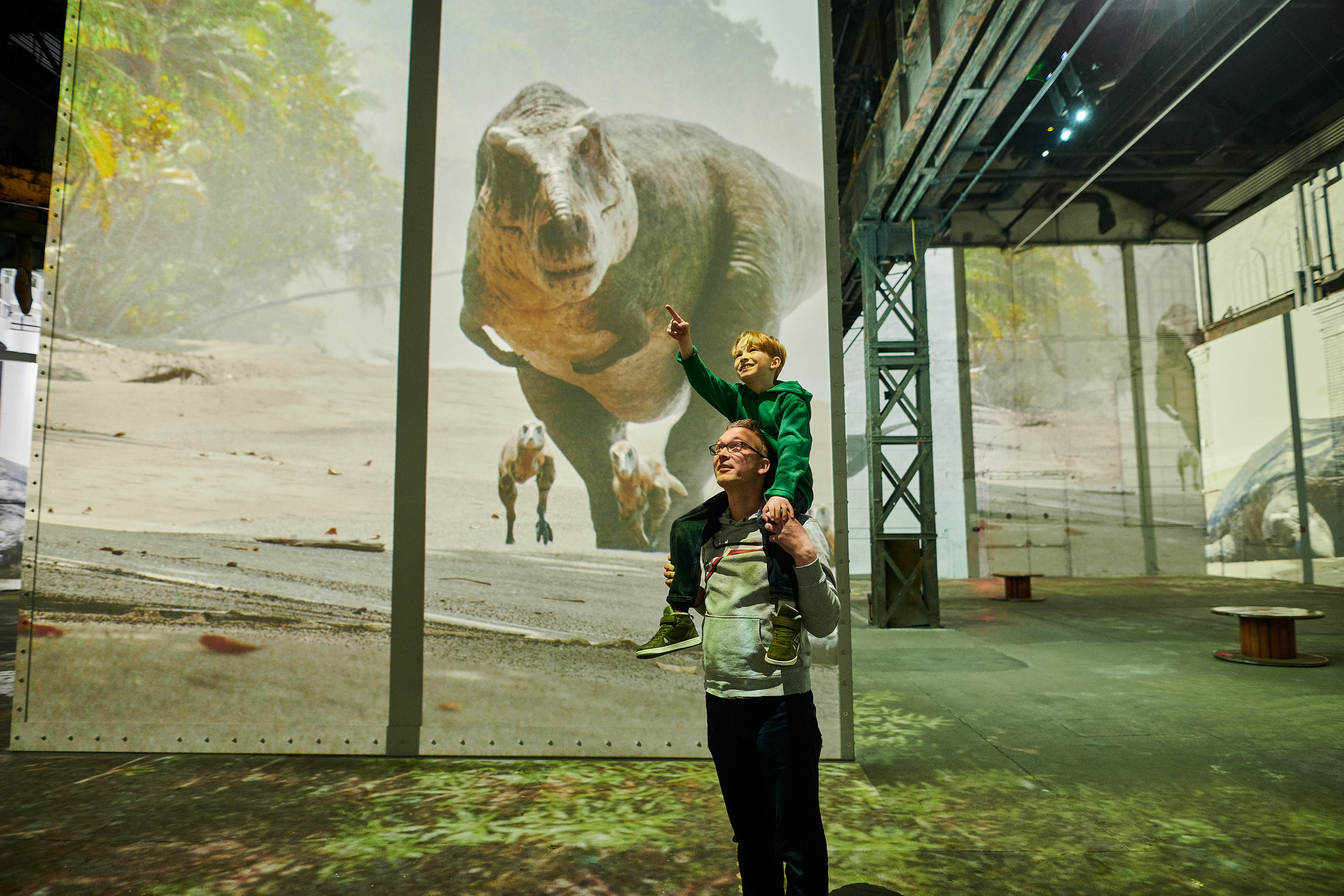 Vater mit Kind auf den Schultern in der immersiven Ausstellung Phoenix des Lumières Dortmund – Dinosaurier-Projektion – Fotograf Markus Mielek