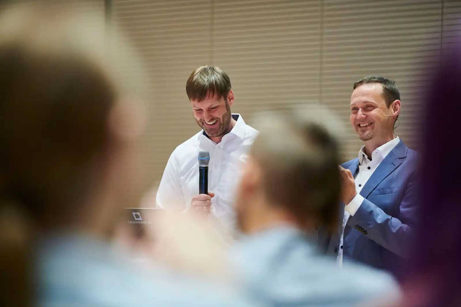 Zwei lachende Männer mit Mikrofon bei einer Unternehmensveranstaltung – Eventfotografie Dortmund, Brockhaus AG am Phoenixsee.