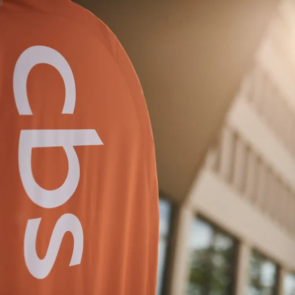 Orangefarbenes CBS-Logo-Banner vor Unternehmensgebäude in Dortmund, Imagefotografie für Corporate Event im Gegenlicht.
