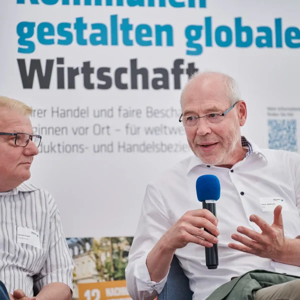 Zwei Männer im Gespräch beim Werkstattgespräch von Engagement Global, einer spricht ins Mikrofon, festgehalten vom Fotografen in Dortmund.